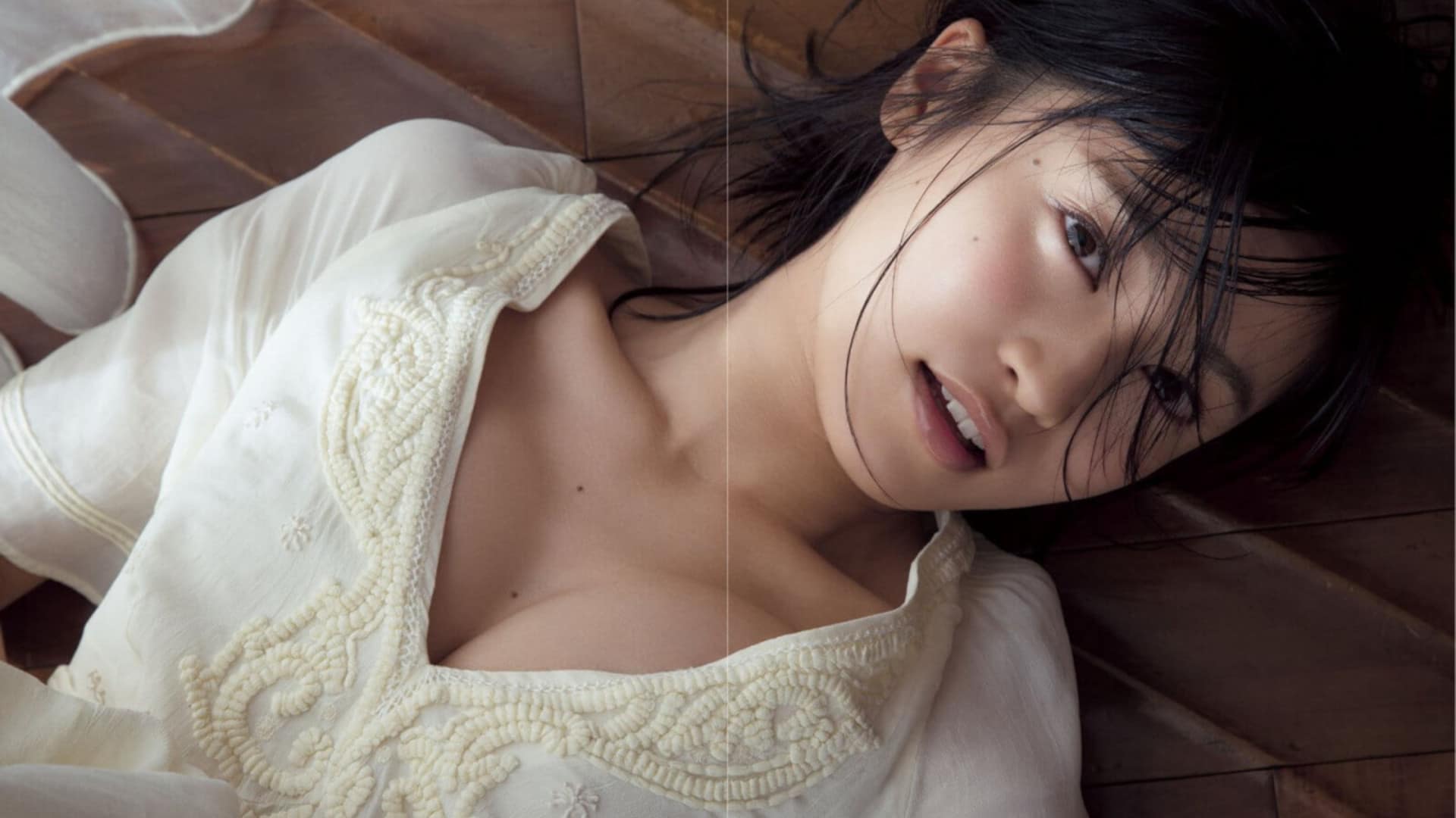 Captivating Asian brunette in casual attire relaxing gracefully on the floor.